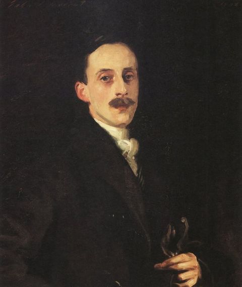 Painting. Shown from the waist up, a pale-skinned man, Hugh Lane, faces and looks at us against a dark background. He has an oval face, a long nose, and a bushy moustache. His dark hair and black coat blend into the shadowy background, and he holds gloves in one long-fingered hand.